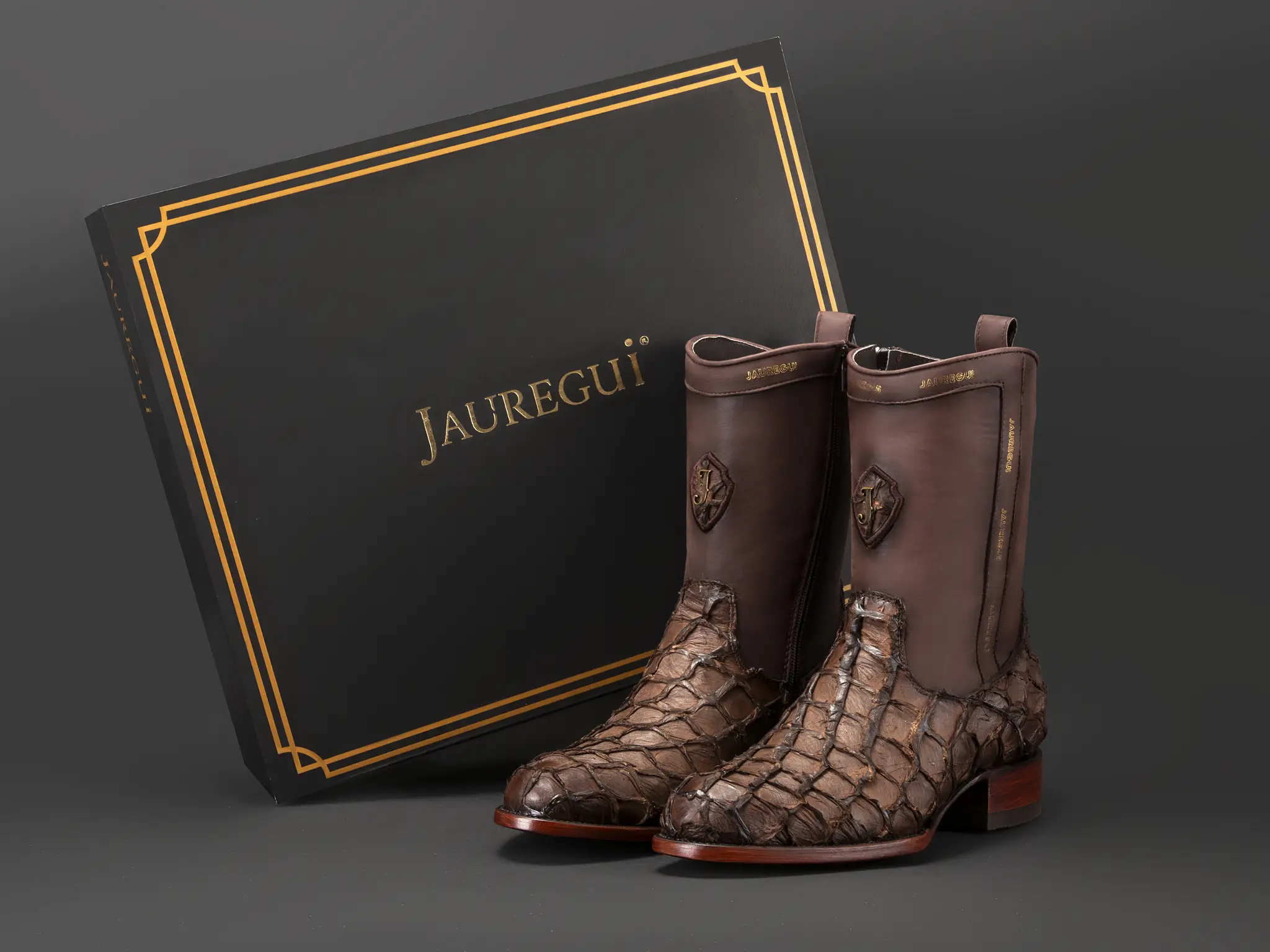 Botas Jauregui de piel de pirarucú café junto a su caja de marca